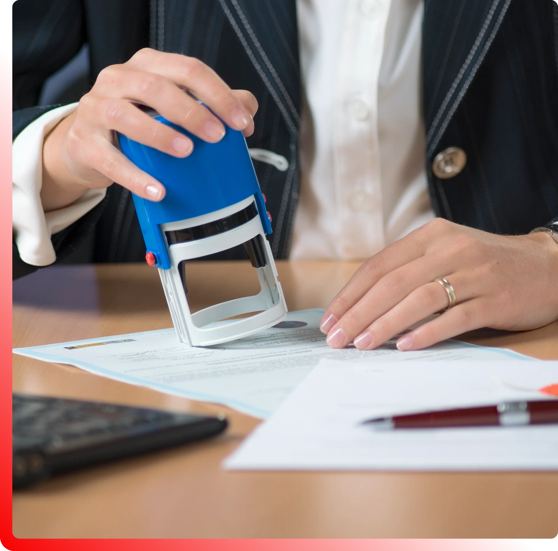 Person stamping a document at a desk, with a calculator and papers nearby.